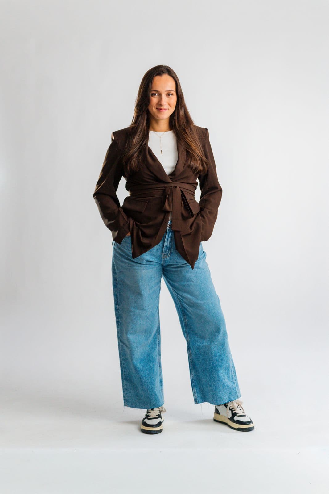 Marie Calasnives en pied, blazer marron noué et jean large, sur fond blanc