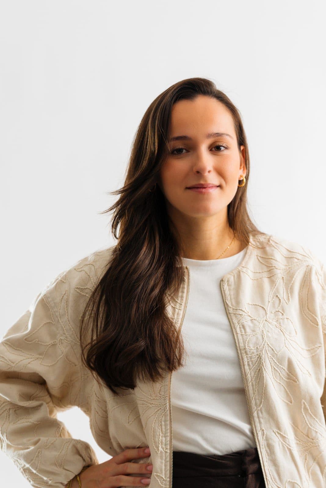 Marie Calasnives en veste crème brodée, la main sur la hanche, sur fond blanc