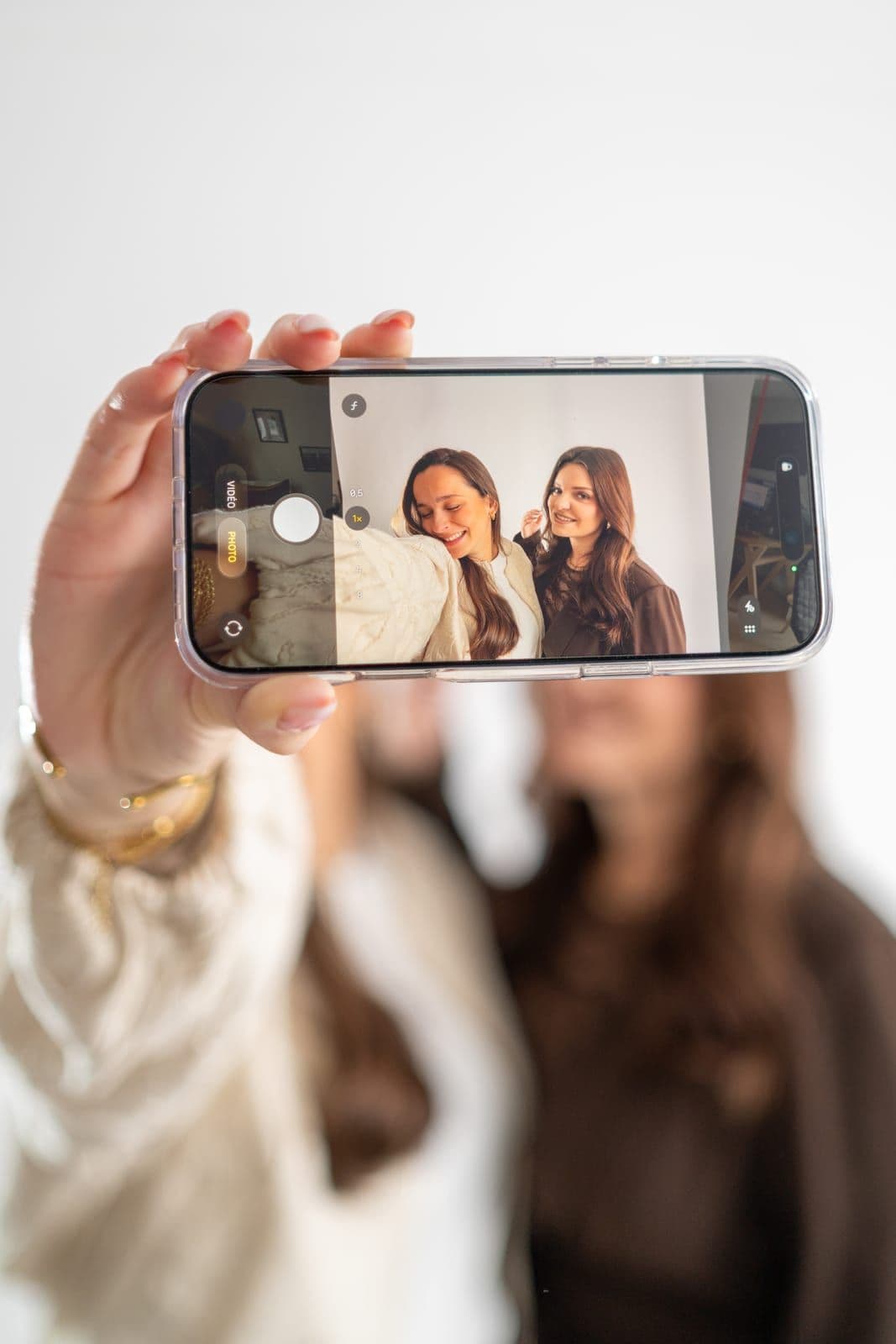 Au premier plan, un téléphone affiche le selfie de deux femmes